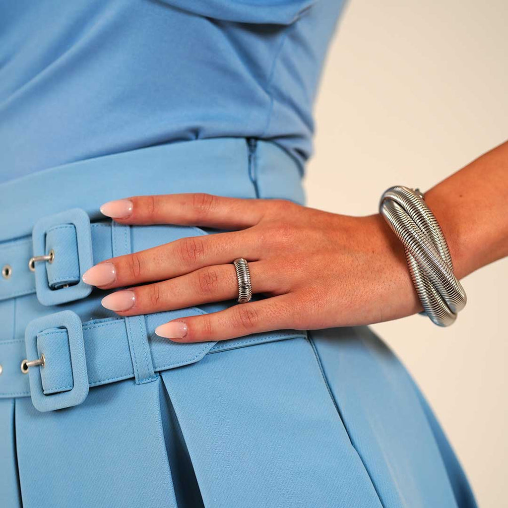 Getragen von Model Armband Raahi und Taora Breiter, offener Ring aus Edelstahl silber mit geriffeltem Design. Stilvolles Accessoire mit modernem Look.